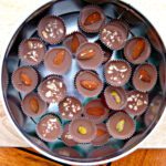 chocolates in a tin topped with various different nuts